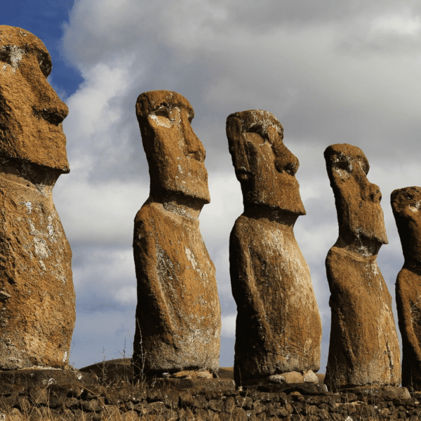 7 Easter Island Statues lined up in a row with blue skies and clouds in the background