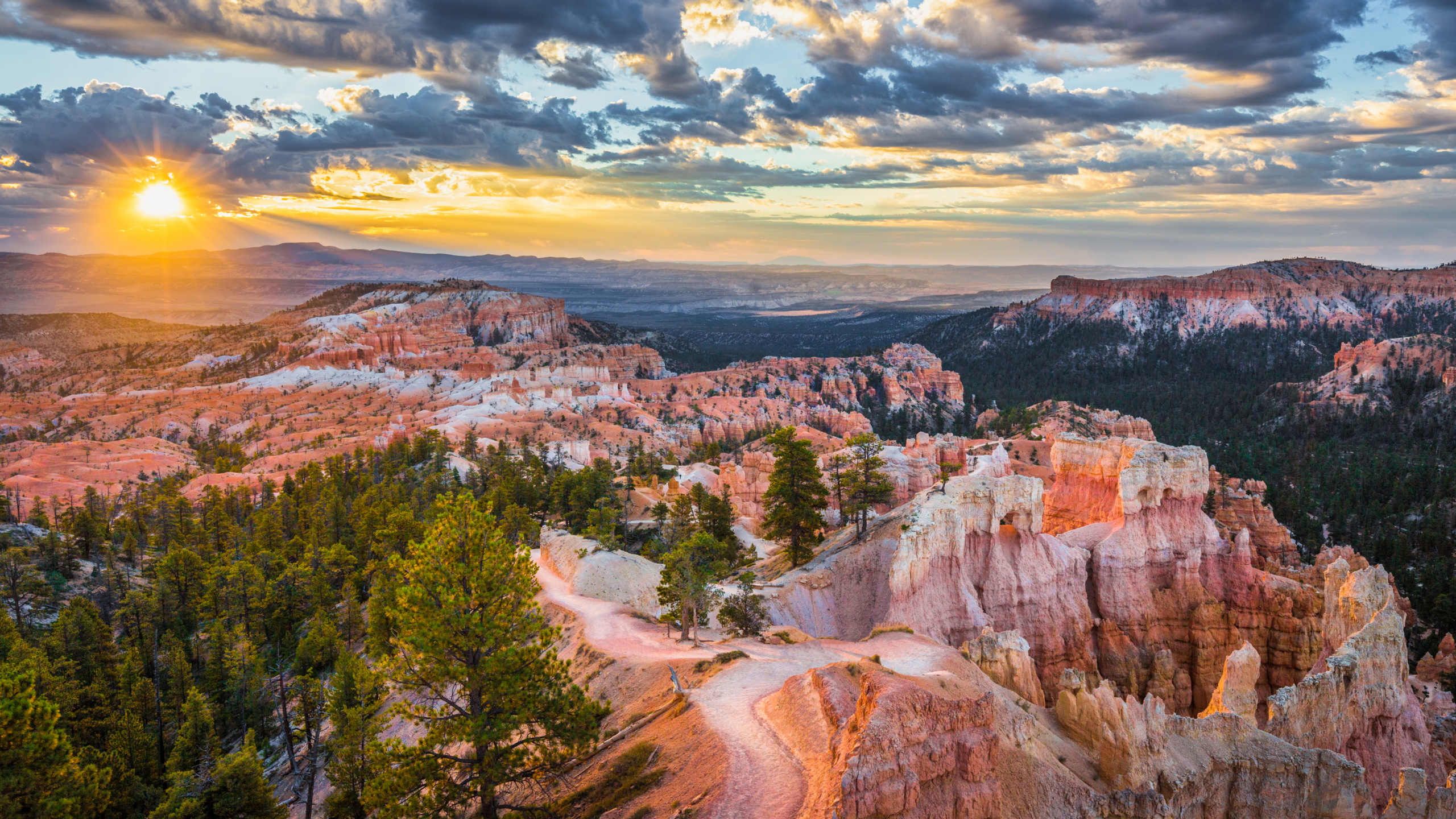hoodoos and hillsides of bryce canyon national park at sunset. the hills are orange and the sky is golden and blue