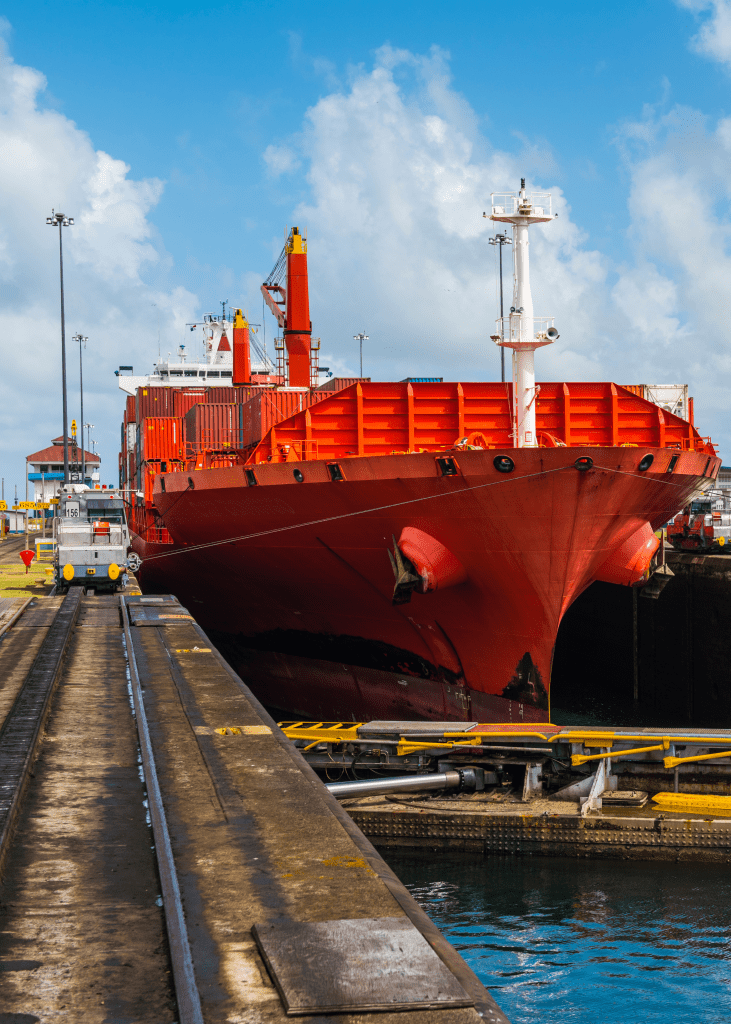 red tanker going through the panama canal with rail next to it