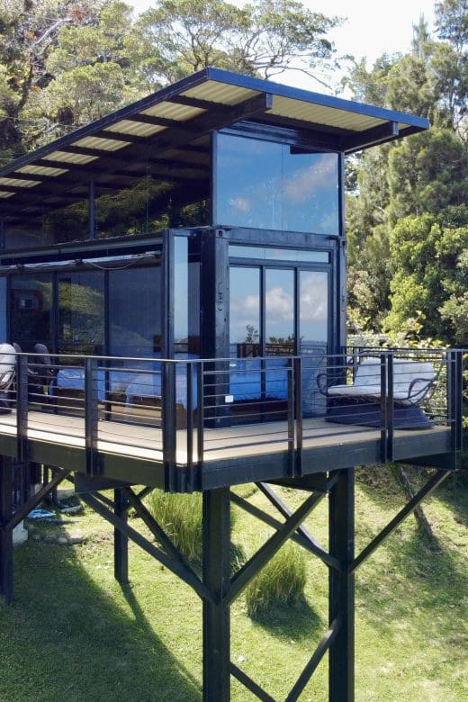 a container home on stilts looking out over rainforest