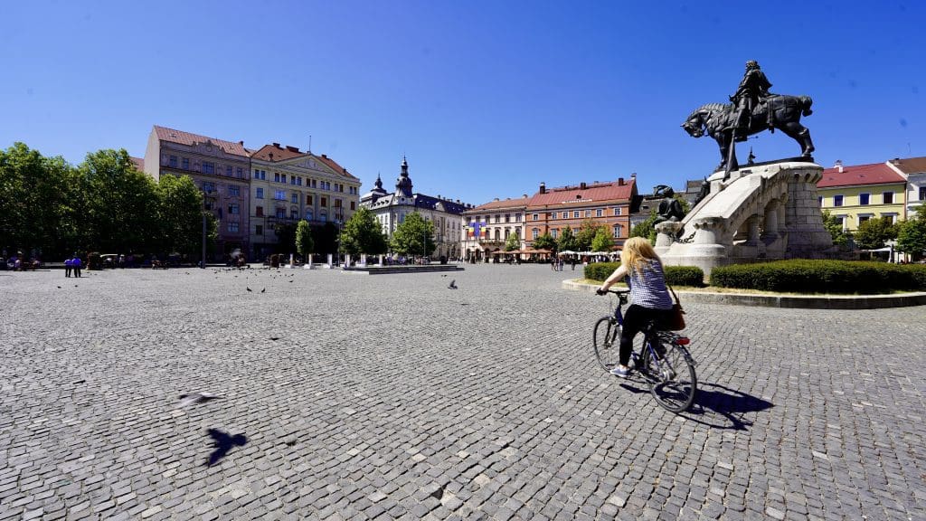 woman riding bike across square
