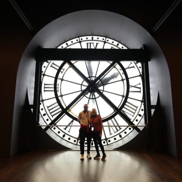 Man and woman standing in front of large clock in the Musee D’Orsay in Paris, France