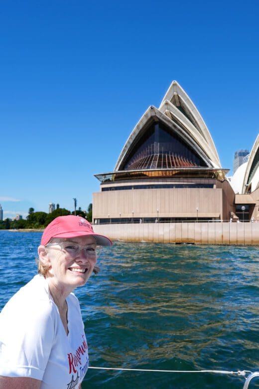 a woman on a boat with a view of the Sydney Opera House from the water
